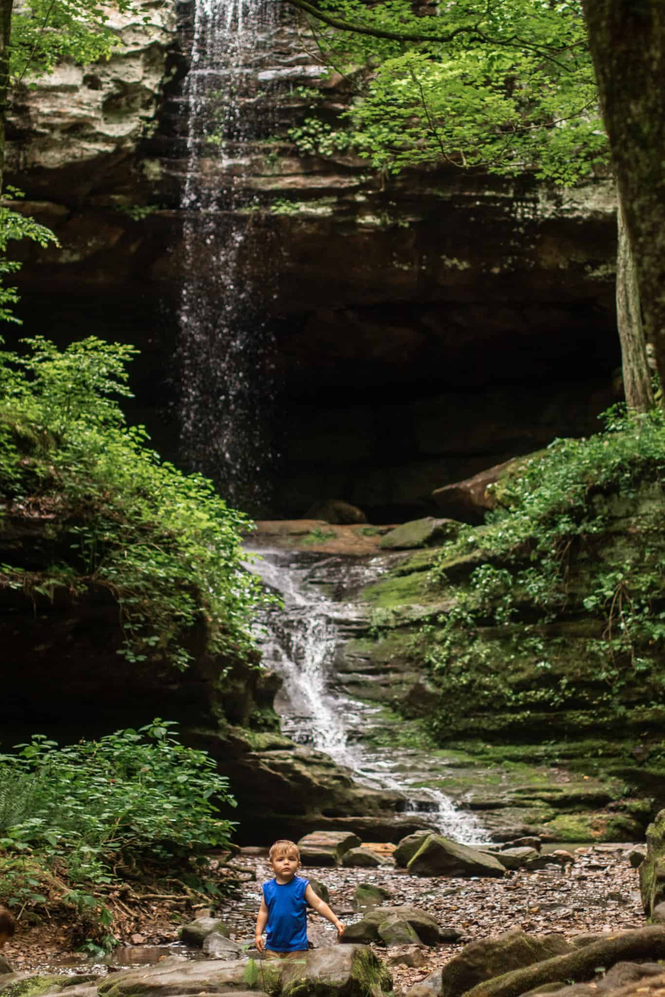 Boy in blue at the bottom of a waterfall