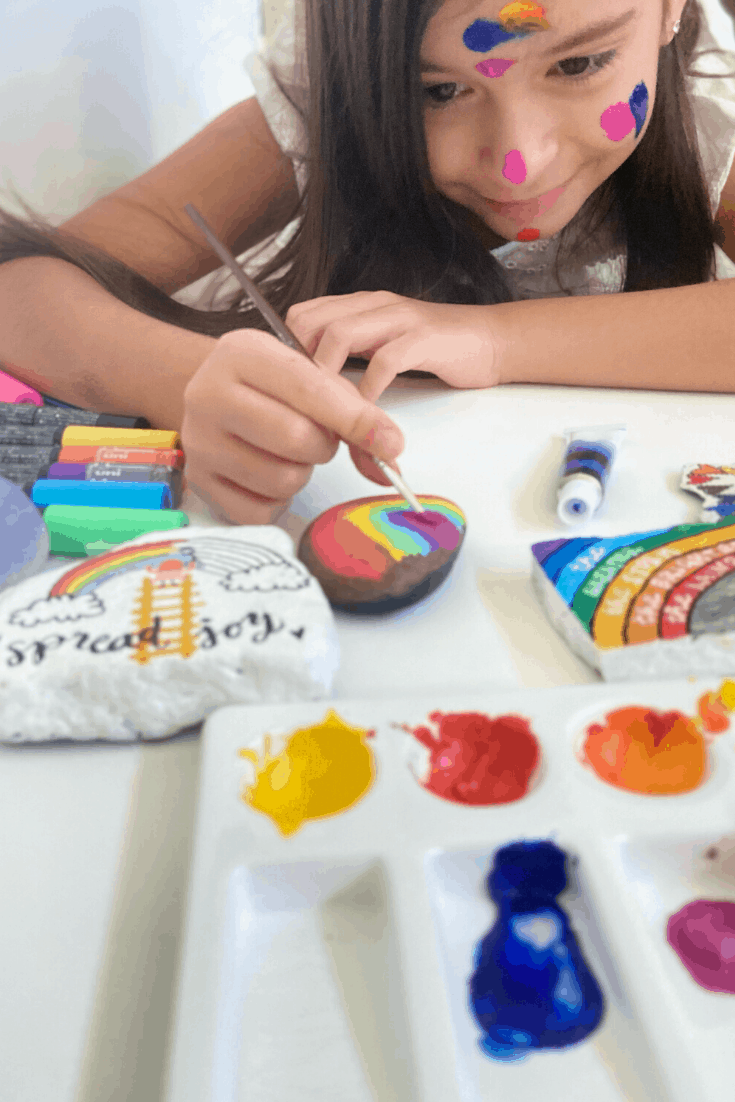 A child laying down while painting rocks