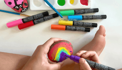 Child Painting a rainbow rock sitting comfortably