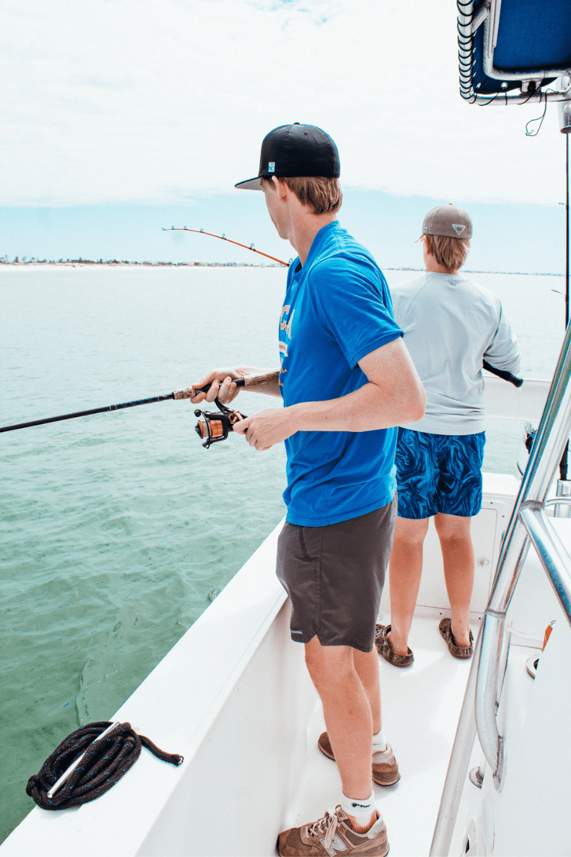 two teen boys fishing off of a fishing charter boat