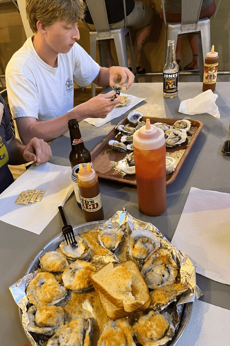 teen boy with a table full of seafood inside Indian Pass Raw Bar restaurant