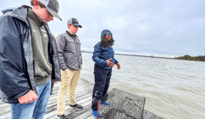 two teen boys standing on a dock with an instructor learning about large size commercial crabbing baskets