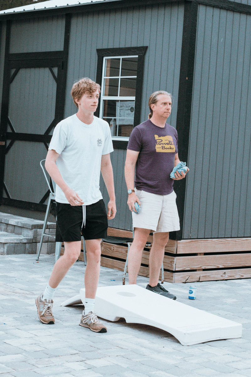 dad and teen son playing lawn games while on vacation at a restaurant