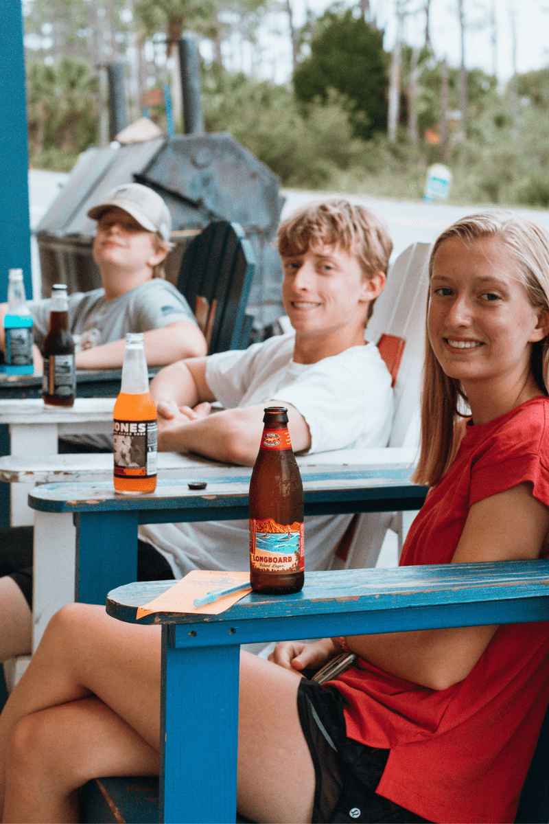 Teens sitting in large wooden chairs with sodas waiting